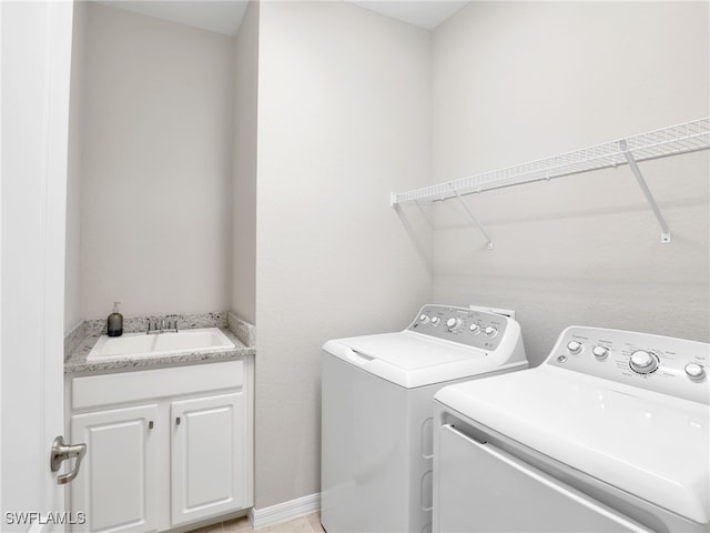 laundry room featuring sink, washer and clothes dryer, and cabinets