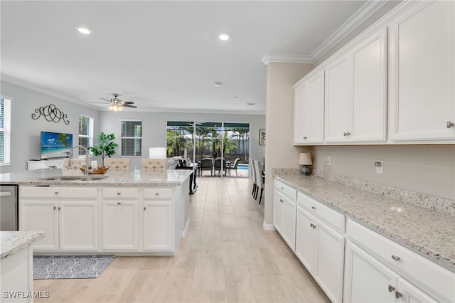 kitchen featuring ceiling fan, ornamental molding, light stone counters, white cabinets, and sink