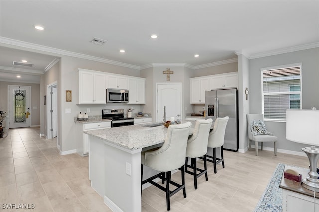 kitchen featuring light stone counters, a center island with sink, white cabinetry, appliances with stainless steel finishes, and sink