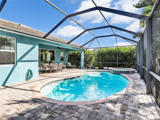 view of pool featuring ceiling fan, a patio, glass enclosure, and an in ground hot tub