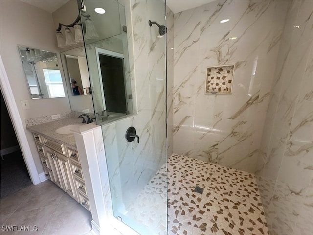 bathroom with tile patterned floors, vanity, and a tile shower