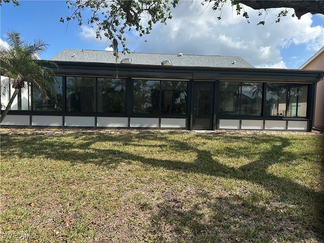 rear view of property featuring a sunroom and a yard