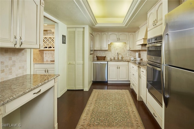 kitchen featuring sink, light stone counters, appliances with stainless steel finishes, dark wood-type flooring, and decorative backsplash