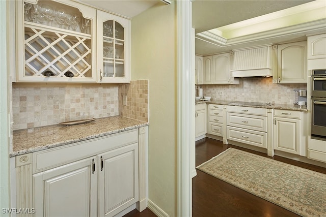 kitchen featuring dark wood-type flooring, tasteful backsplash, light stone countertops, and black electric stovetop