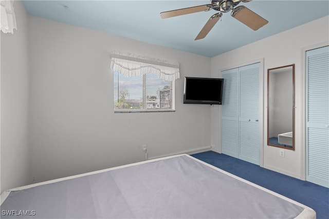 unfurnished bedroom with carpet, ceiling fan, and multiple closets