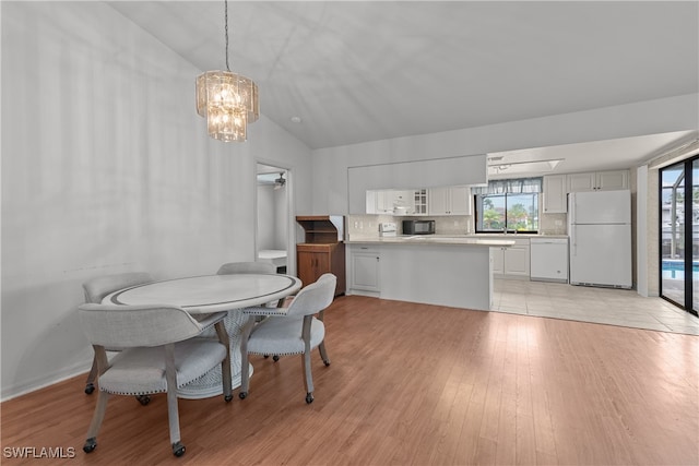 dining space with a healthy amount of sunlight, ceiling fan with notable chandelier, light hardwood / wood-style flooring, and lofted ceiling