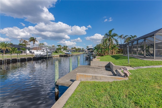 dock area with a water view, a lanai, and a lawn