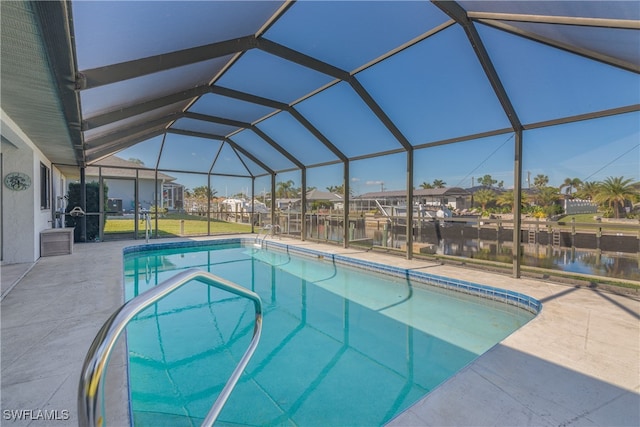 view of swimming pool featuring glass enclosure, a water view, and a patio