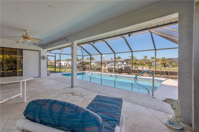 view of swimming pool with ceiling fan, a lanai, and a patio