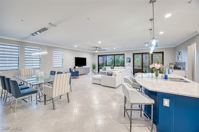 tiled dining space featuring ornamental molding, sink, and ceiling fan