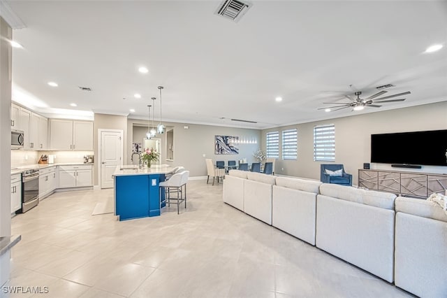 tiled living room featuring ornamental molding, sink, and ceiling fan