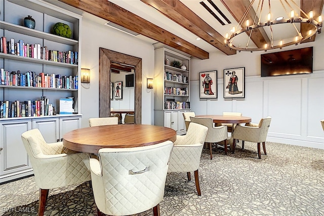 dining area featuring beamed ceiling, built in features, and an inviting chandelier