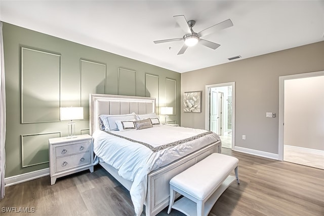 bedroom featuring ceiling fan, ensuite bath, and wood-type flooring