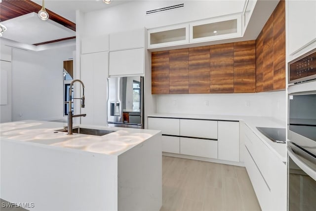 kitchen featuring stainless steel appliances, sink, light hardwood / wood-style flooring, and white cabinets