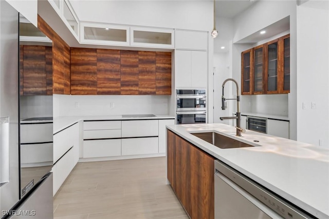 kitchen featuring sink, beverage cooler, white cabinets, and appliances with stainless steel finishes