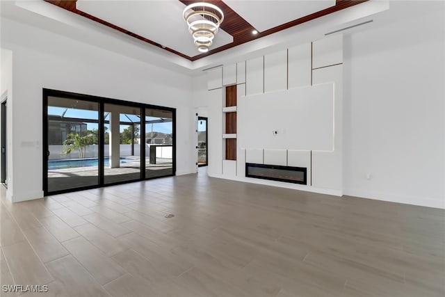 unfurnished living room featuring an inviting chandelier, wood ceiling, and a raised ceiling