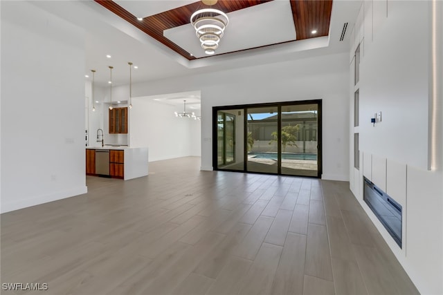 unfurnished living room featuring wooden ceiling, a raised ceiling, sink, and a notable chandelier