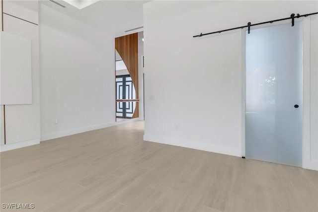 spare room featuring light hardwood / wood-style flooring and a barn door