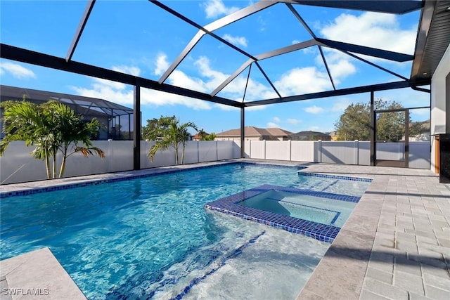 view of pool with an in ground hot tub, a patio area, and glass enclosure