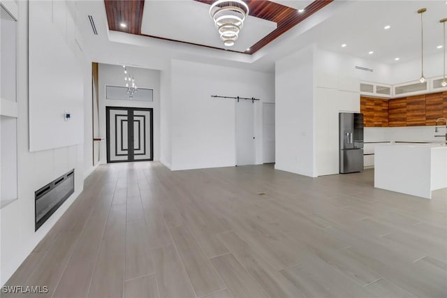 unfurnished living room featuring a towering ceiling, light hardwood / wood-style floors, and ceiling fan with notable chandelier