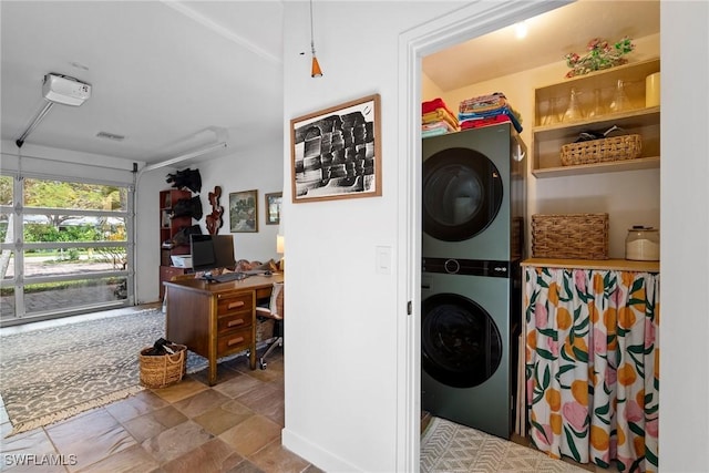 washroom featuring laundry area, stone finish flooring, a garage, and stacked washing maching and dryer