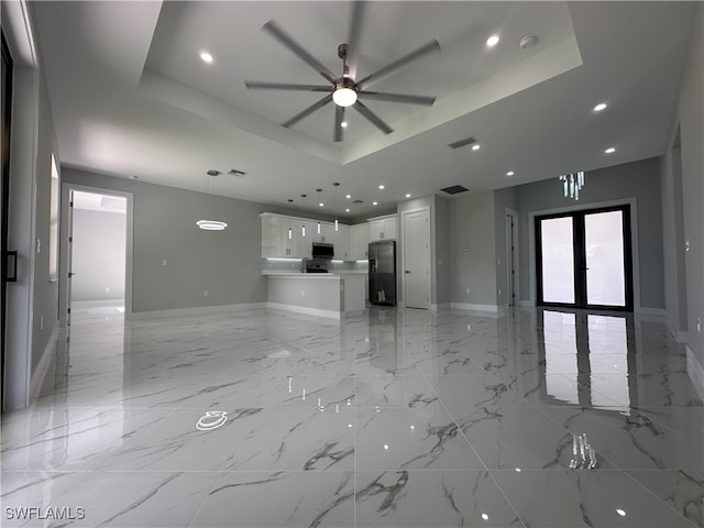 unfurnished living room featuring french doors, ceiling fan, and a raised ceiling