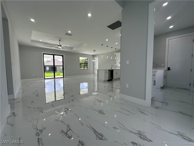 unfurnished living room featuring a tray ceiling and ceiling fan