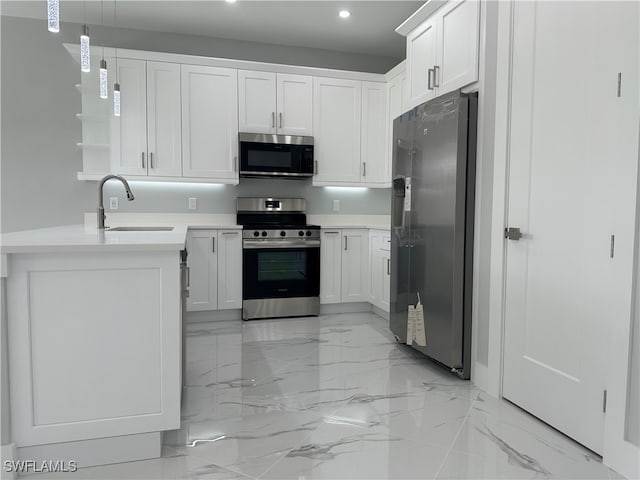 kitchen with white cabinets, kitchen peninsula, sink, appliances with stainless steel finishes, and decorative light fixtures