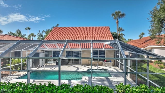 rear view of property with glass enclosure and a patio