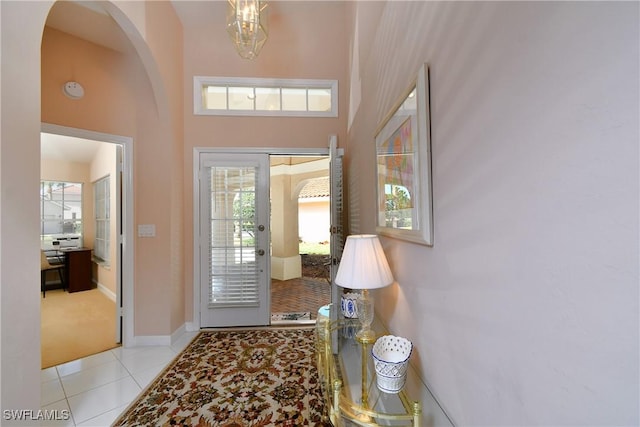 entrance foyer with light tile patterned flooring, a towering ceiling, and an inviting chandelier