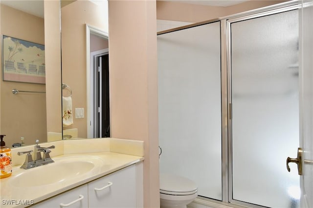 bathroom with a shower with door, vanity, and toilet