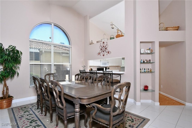 dining space with light tile patterned floors and high vaulted ceiling