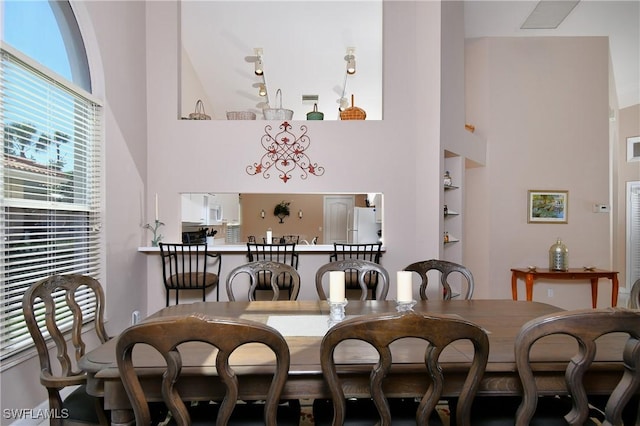 dining room with built in shelves and a high ceiling