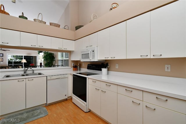 kitchen with white appliances, white cabinetry, and sink