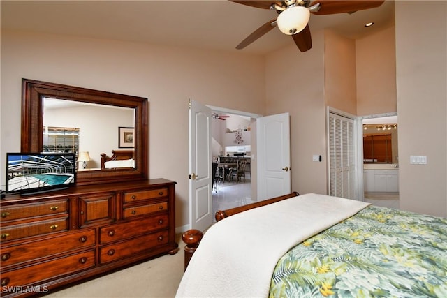 bedroom featuring light carpet, ensuite bathroom, ceiling fan, a closet, and lofted ceiling