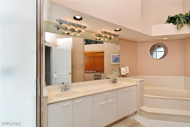 bathroom with tile patterned floors, a washtub, and vanity