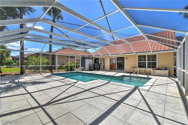 view of pool with glass enclosure and a patio area