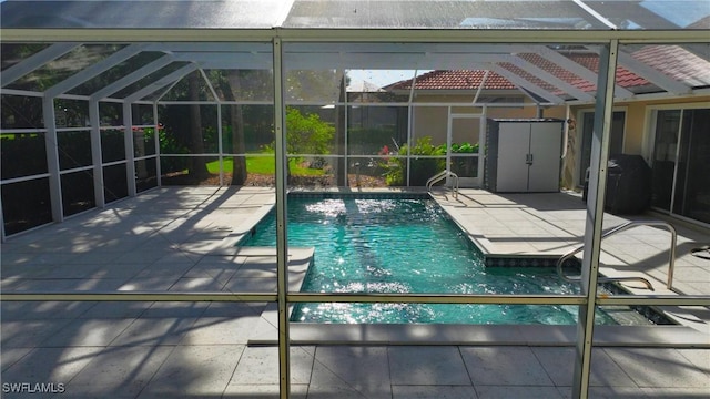 view of swimming pool with glass enclosure, a grill, and a patio