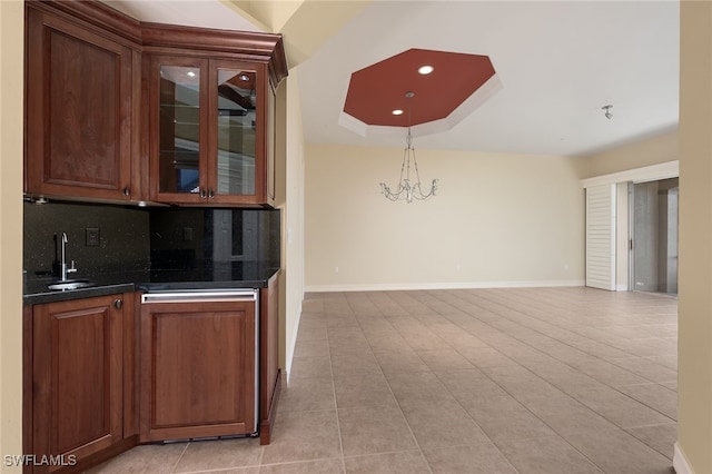 bar featuring a chandelier, baseboards, a sink, and decorative backsplash