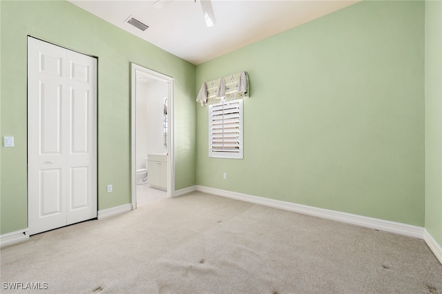 unfurnished bedroom with ceiling fan, light carpet, and connected bathroom