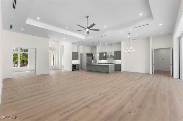 3509 5th Ave SW, Naples, FL 34117 - unfurnished living room featuring a tray ceiling, ceiling fan, recessed lighting, light wood-type flooring, and a chandelier