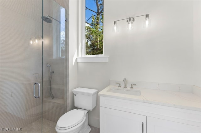 bathroom with vanity, toilet, and a shower with door