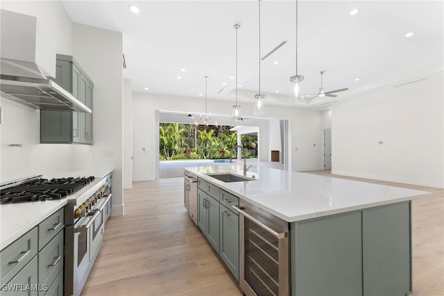 kitchen featuring beverage cooler, hanging light fixtures, sink, an island with sink, and appliances with stainless steel finishes