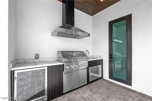 kitchen with light stone countertops, wall chimney range hood, sink, and wood ceiling