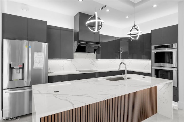 kitchen with sink, stainless steel appliances, tasteful backsplash, an island with sink, and pendant lighting