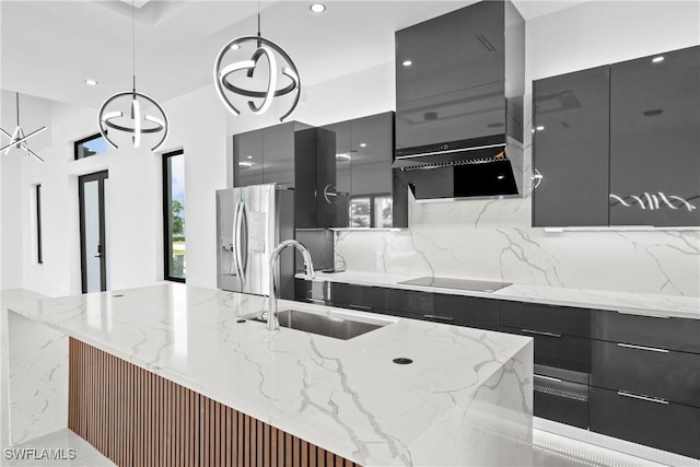 kitchen with stainless steel fridge with ice dispenser, light stone countertops, sink, and hanging light fixtures