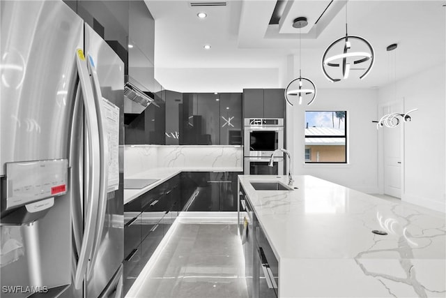 kitchen with light stone countertops, sink, a notable chandelier, pendant lighting, and appliances with stainless steel finishes