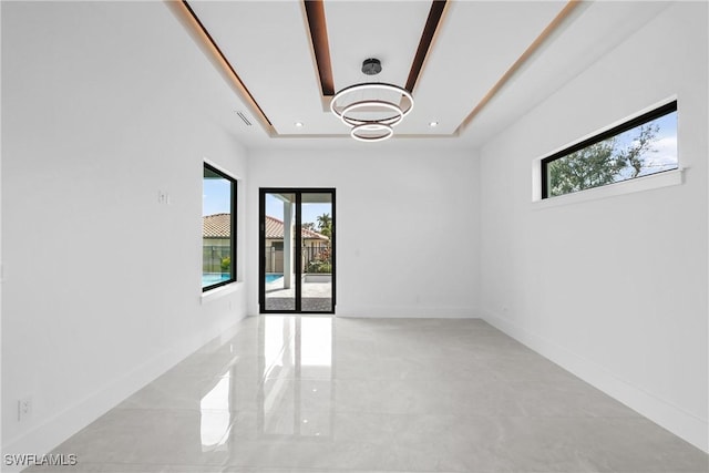 unfurnished room with a tray ceiling, plenty of natural light, and french doors