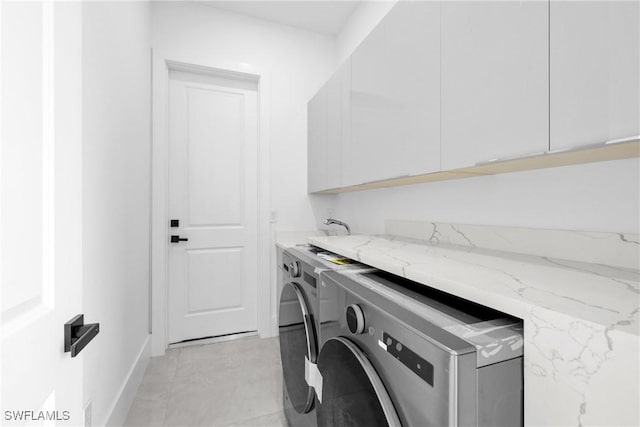 laundry room with washing machine and clothes dryer and cabinets