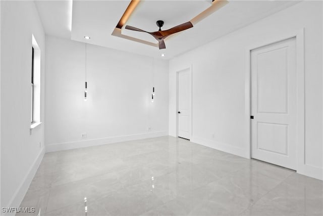 unfurnished room with ceiling fan and a raised ceiling